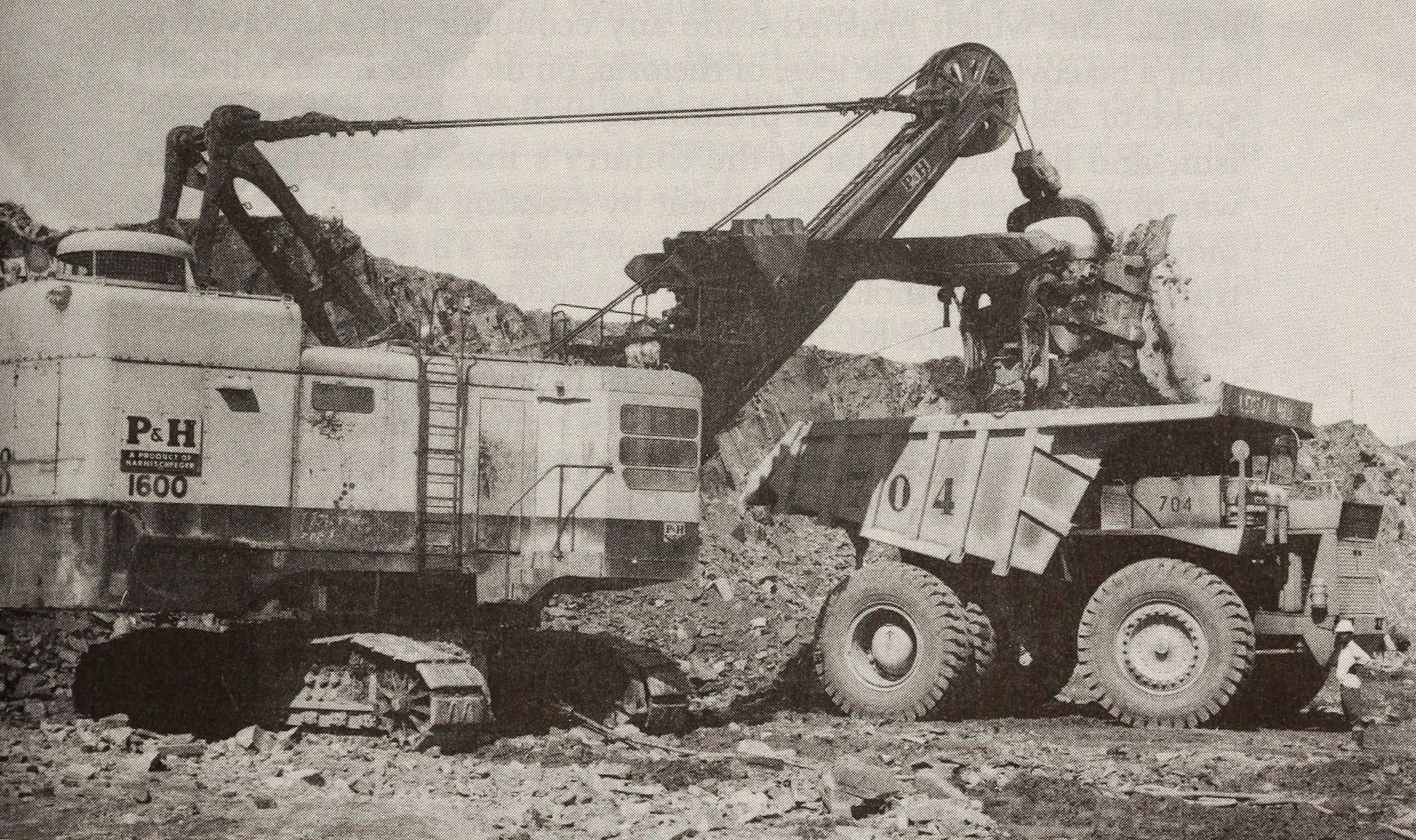 Black and white archive photo: a power shovel loads copper and cobalt ore into a truck at Musonoi Mine